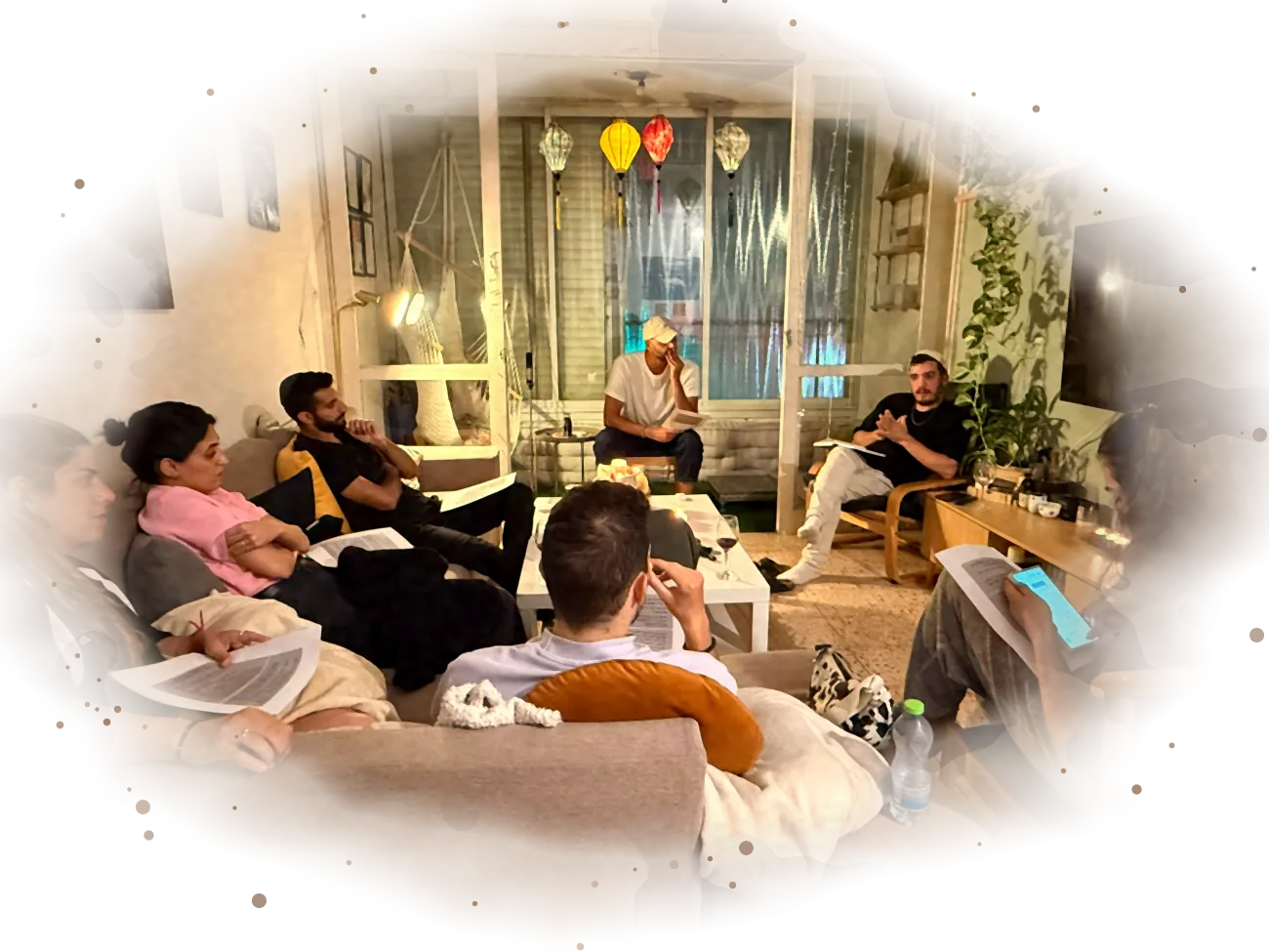 יוסף מעביר שיעור בסלון, המשתתפים מקשיבים עם דפי לימוד